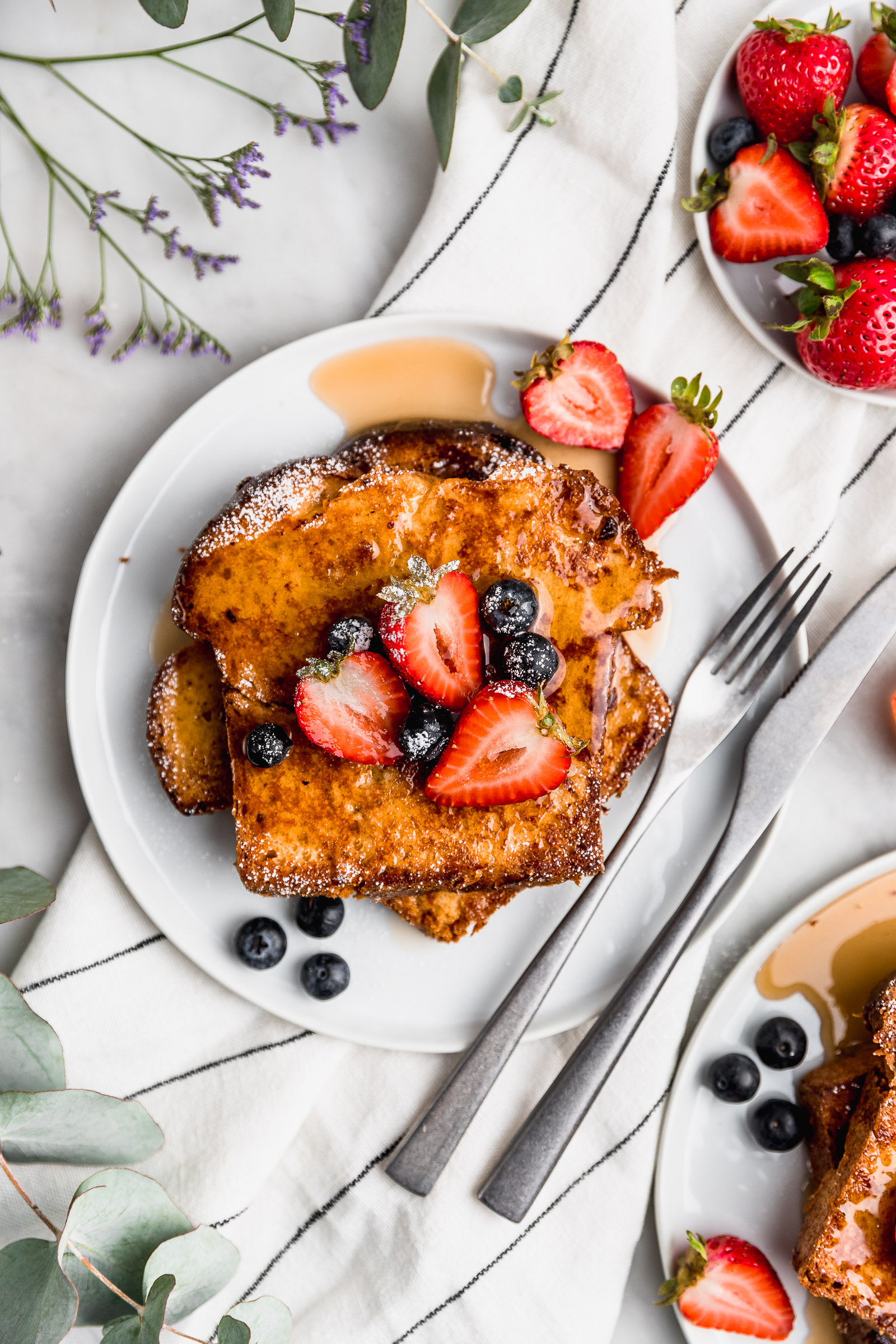 Closeup brioche french toast with icing sugar, maple syrup and berries
