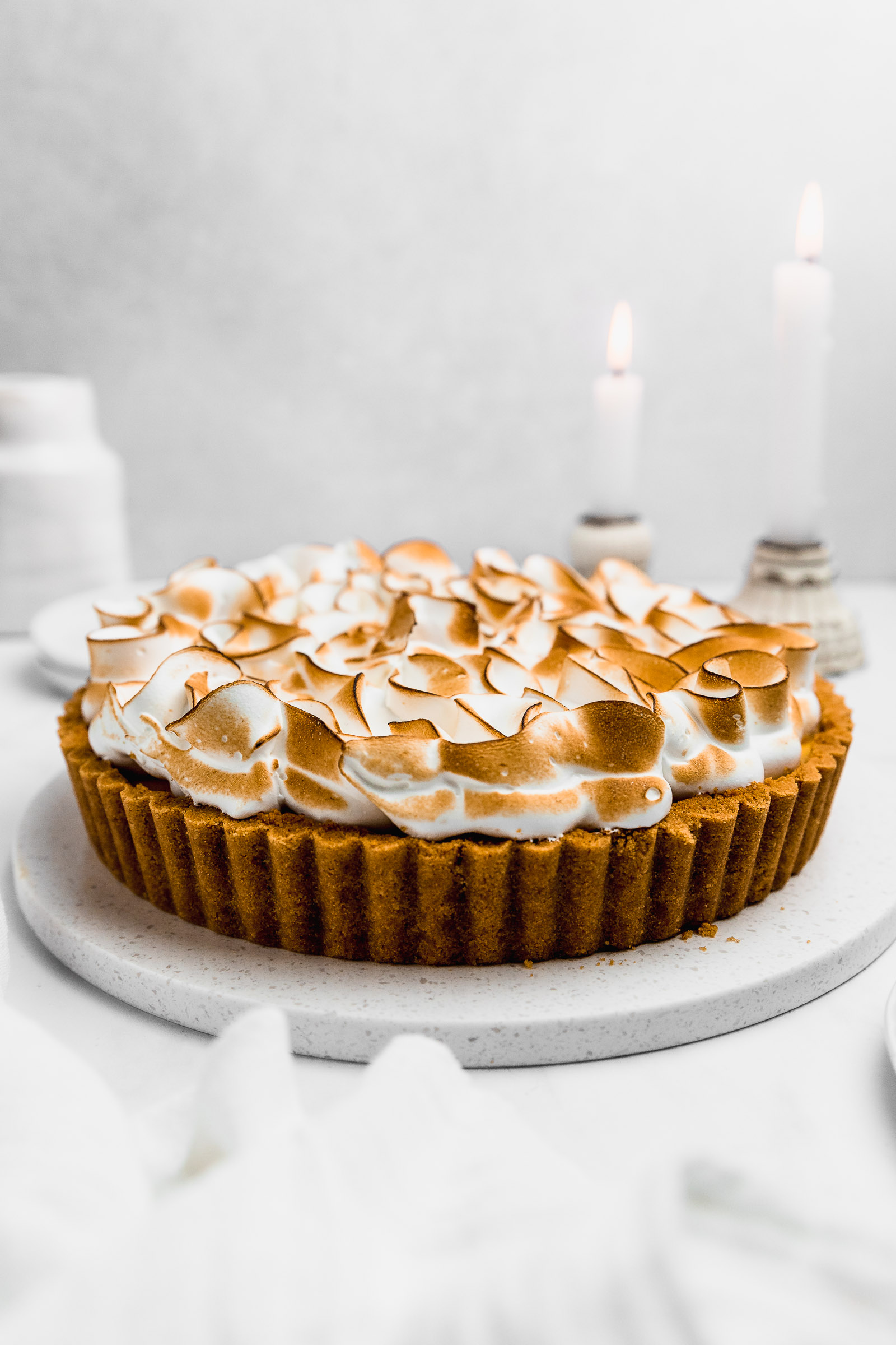Side view of a passion fruit meringue pie with a biscuit base, blowtorched italian meringue on top. 