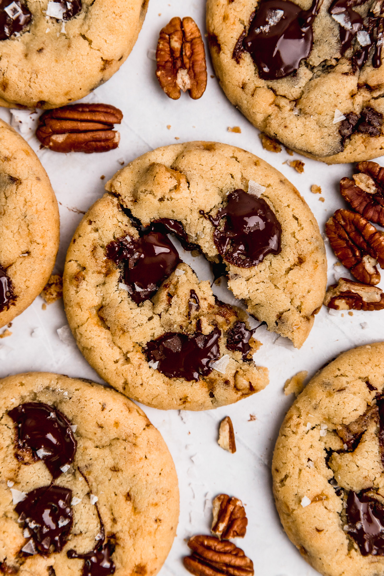 Pecan Praline Chocolate Chip Cookies, one cut in half with chocolate oozing out.