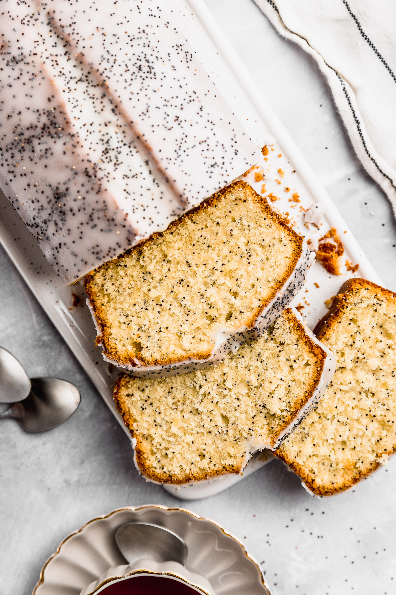 Lemon Poppy Seed Loaf with Lemon Glaze, with three slices cut to show the inside.
