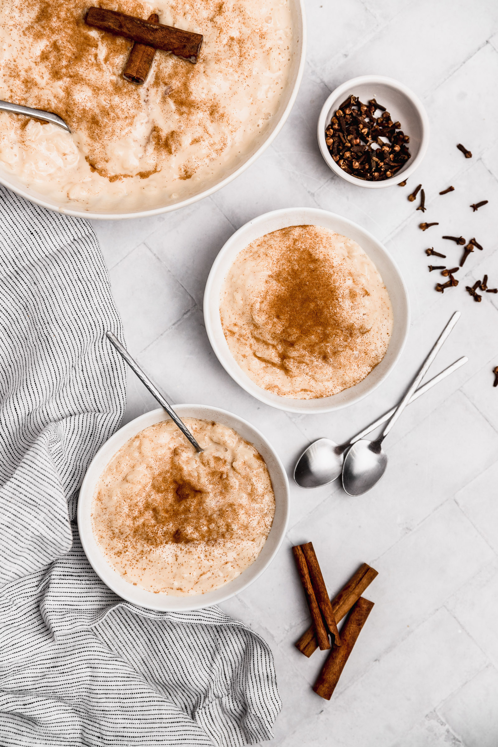 two served bowls of rice pudding with  condensed milk, topped with ground cinnamon.