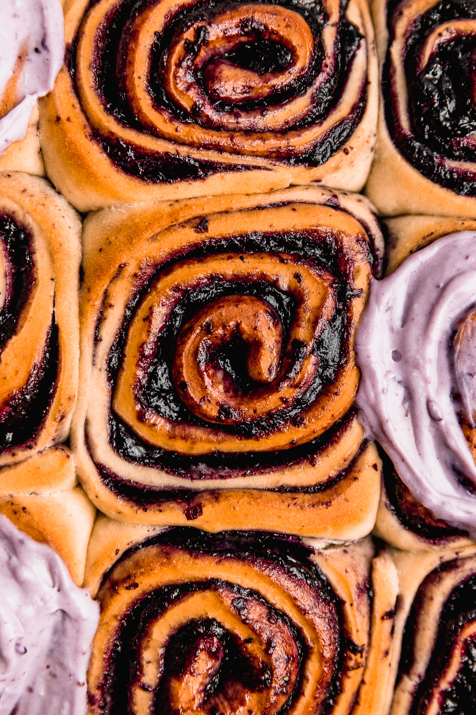 Zoomed in Blueberry Cinnamon Rolls (Blueberry Rolls), with some of them topped with blueberry cream cheese frosting.