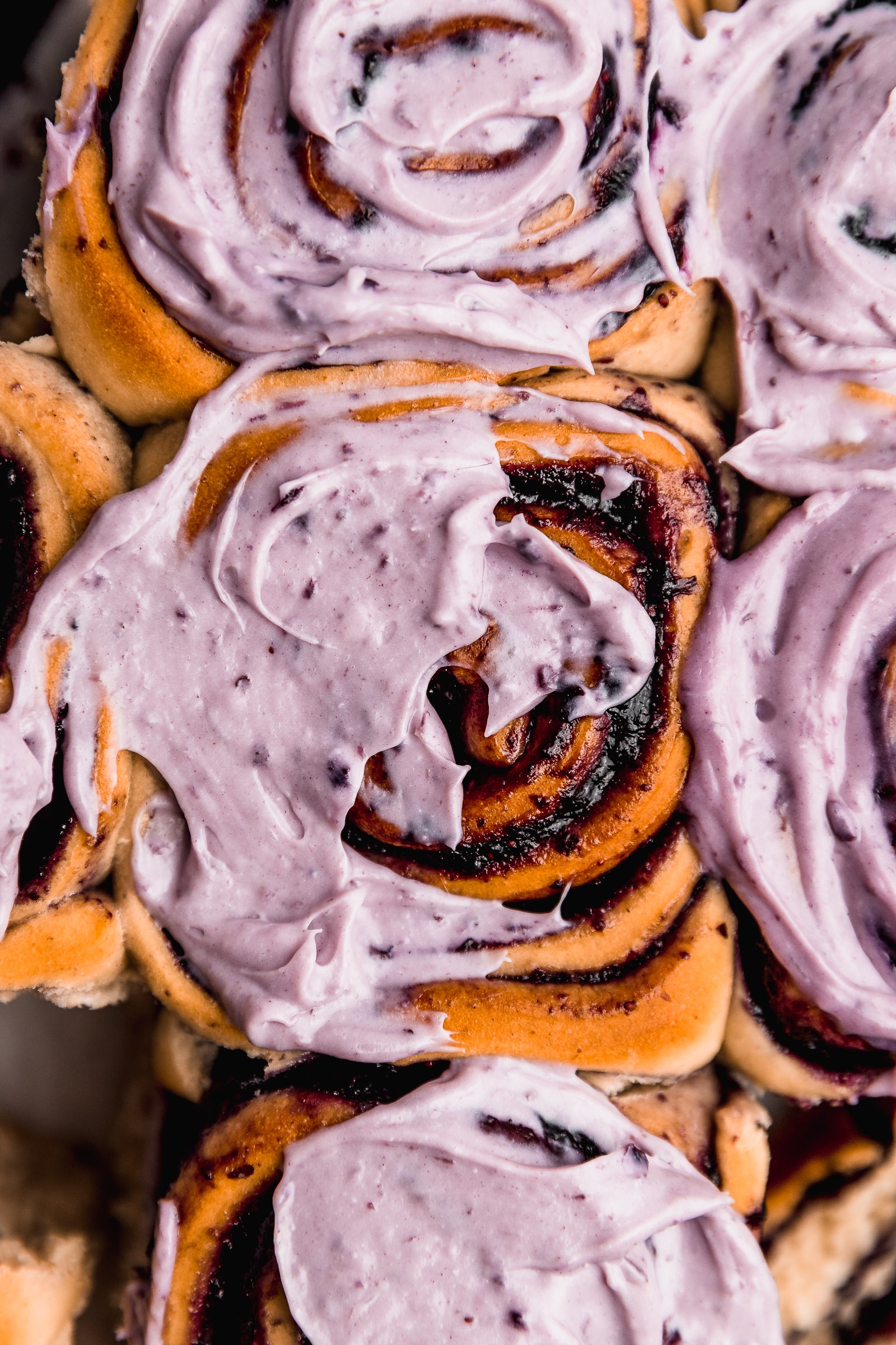 Closeup of Blueberry Cinnamon Rolls (Blueberry Rolls), topped with blueberry cream cheese frosting.