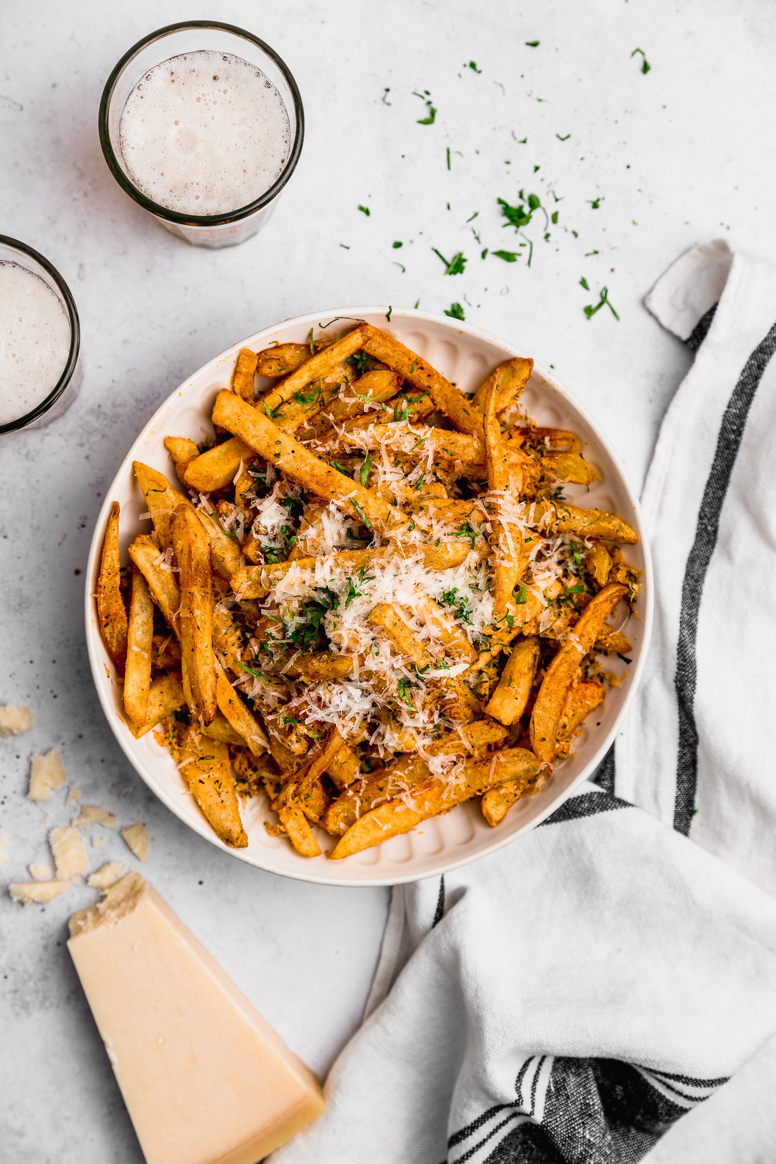 Large bowl of garlic parmesan fries, serve with chopped fresh parsley. You can see they're golden and crispy.