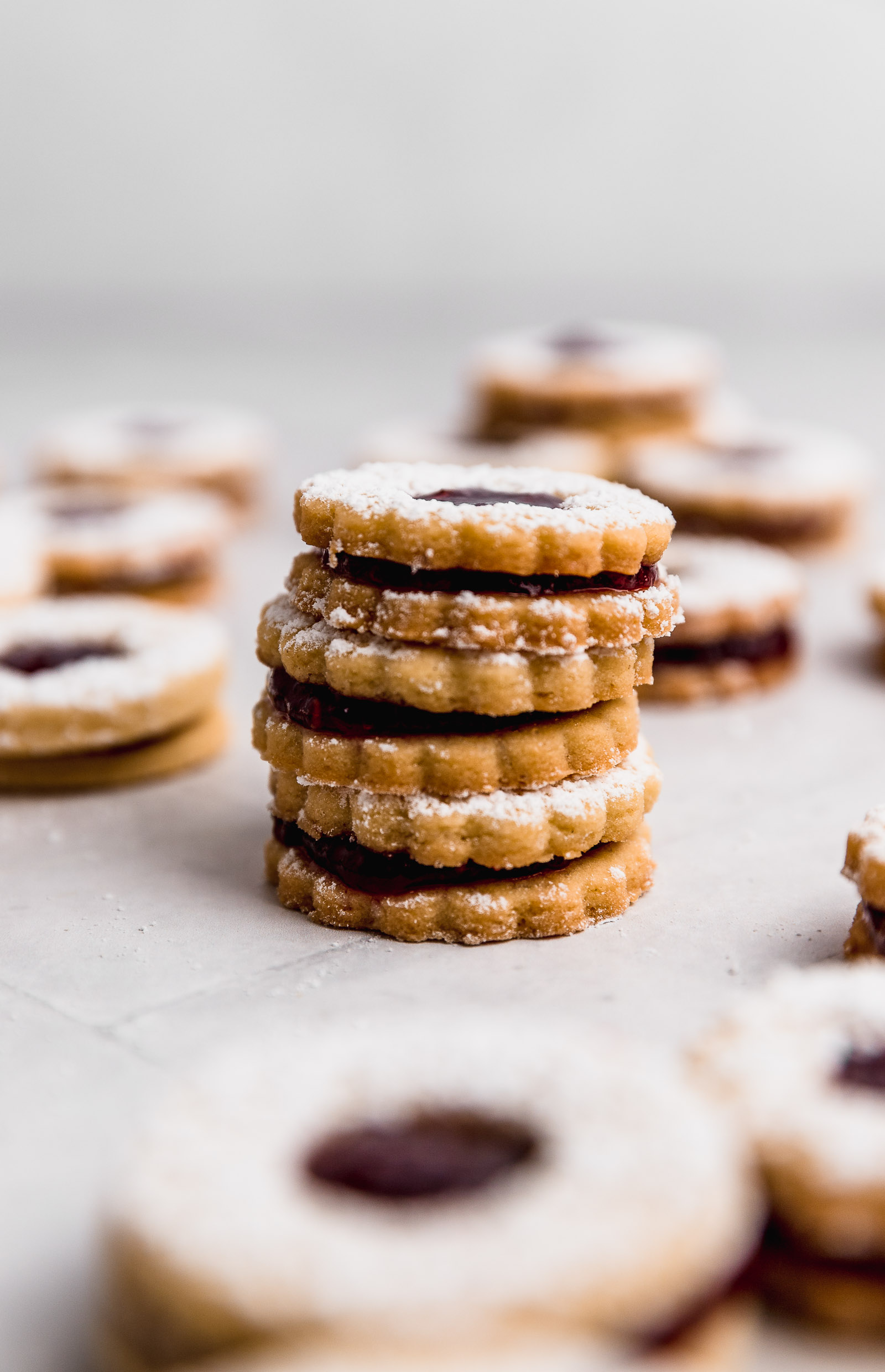 Side view of nut-free linzer cookies where you can see the thickness of the cookies and the raspberry filling.